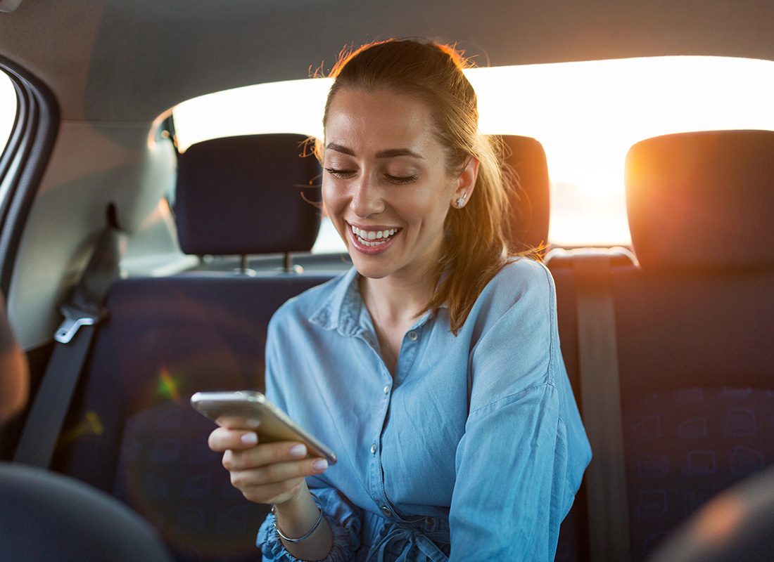 Resources - Young Woman Using Her Smartphone in the Back Seat of a Car